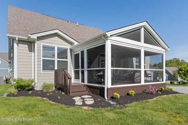 rear view of house featuring a yard, a shingled roof, central AC unit, and a sunroom