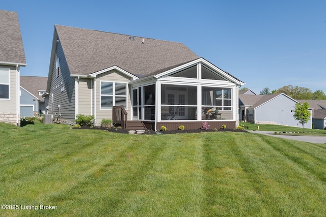 back of property with a yard, cooling unit, a shingled roof, and a sunroom