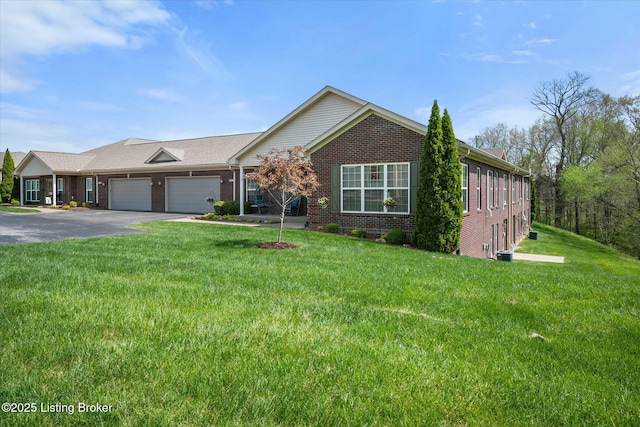 ranch-style home with brick siding, an attached garage, a front yard, and aphalt driveway