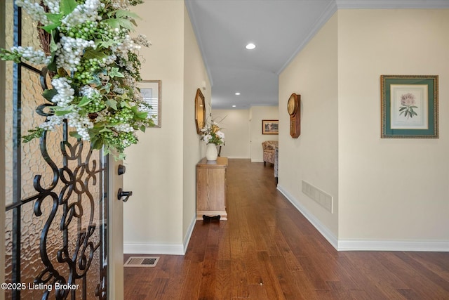 hall featuring baseboards, visible vents, recessed lighting, wood finished floors, and crown molding