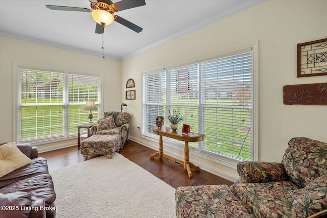 living area with wood finished floors, baseboards, ceiling fan, and crown molding