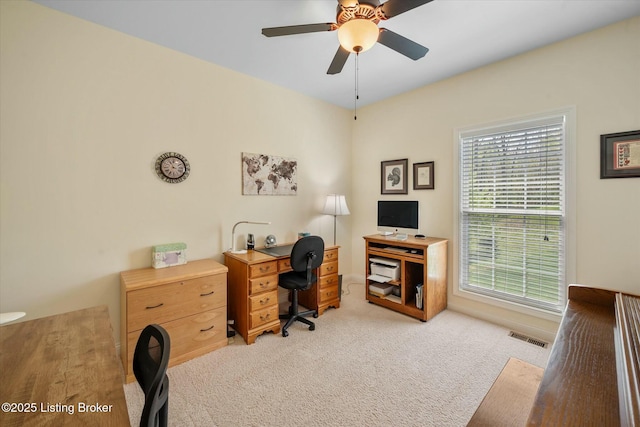 office space featuring light carpet, a ceiling fan, visible vents, and a healthy amount of sunlight