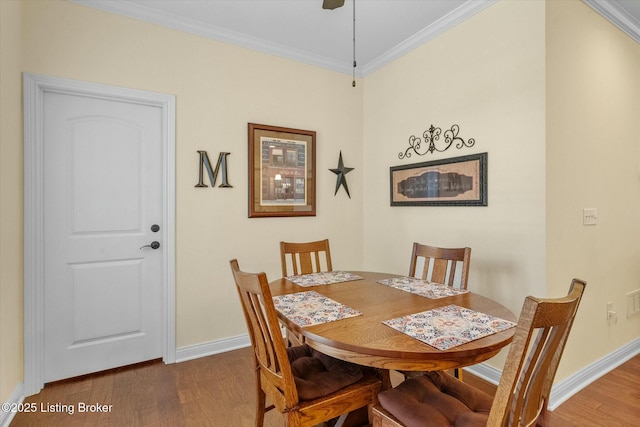 dining space featuring wood finished floors, baseboards, and ornamental molding