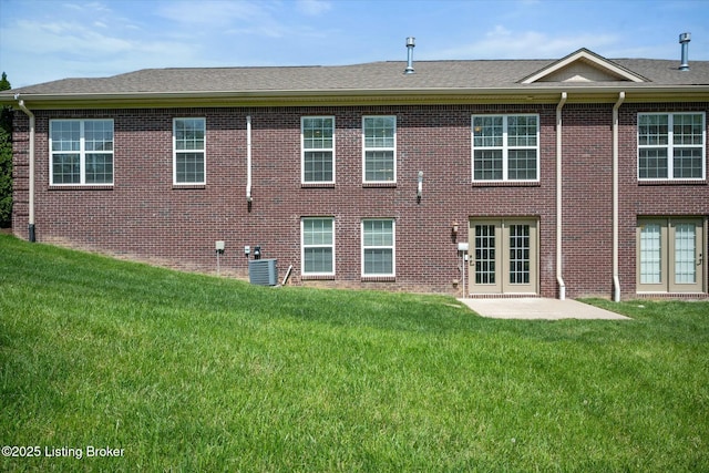back of house with brick siding, central air condition unit, and a lawn