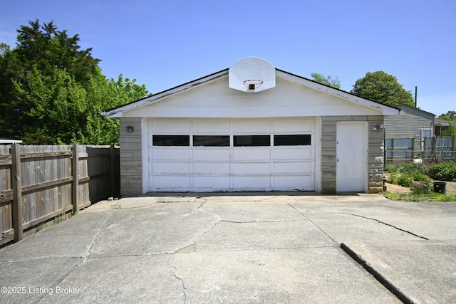 detached garage featuring fence and driveway