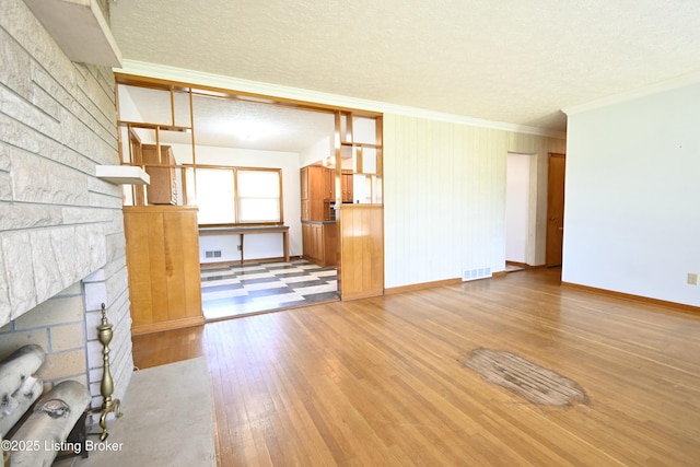 unfurnished living room featuring baseboards, ornamental molding, wood-type flooring, and visible vents