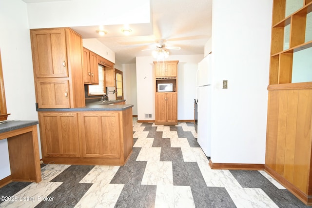 kitchen with a ceiling fan, dark countertops, wall oven, baseboards, and freestanding refrigerator
