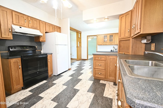 kitchen with freestanding refrigerator, dark countertops, under cabinet range hood, a sink, and black / electric stove