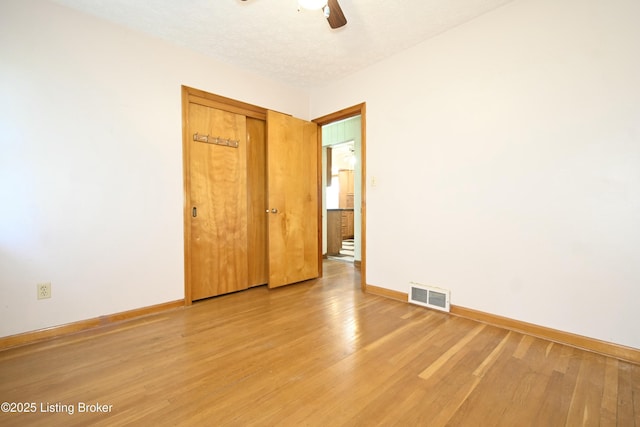 empty room featuring visible vents, baseboards, ceiling fan, and light wood finished floors