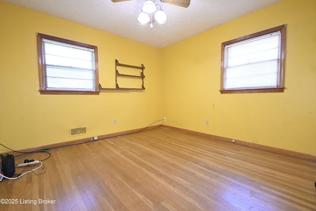 spare room with plenty of natural light, a ceiling fan, light wood-type flooring, and visible vents