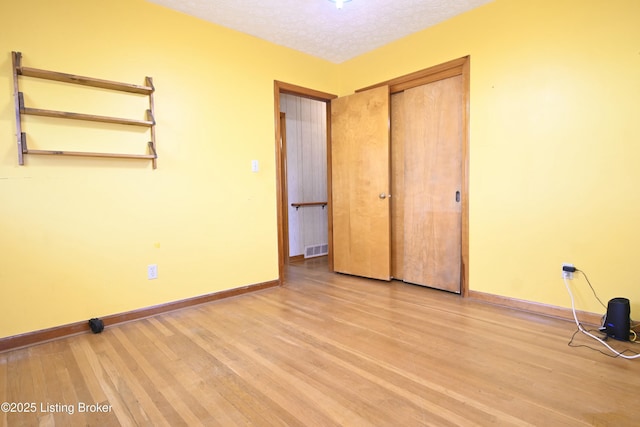 unfurnished bedroom featuring baseboards, a closet, light wood-type flooring, and visible vents