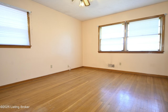 spare room with baseboards, plenty of natural light, light wood-style flooring, and visible vents