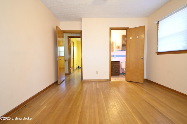 unfurnished room featuring a textured ceiling, baseboards, and light wood-style flooring