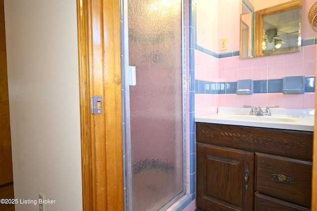 full bathroom with vanity, tile walls, backsplash, and a shower stall