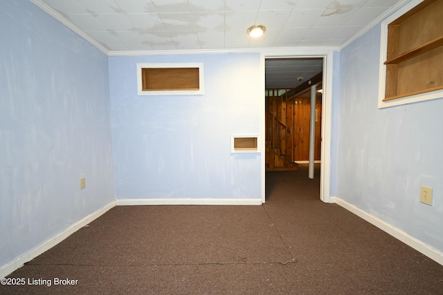 finished below grade area featuring baseboards, ornamental molding, and dark colored carpet