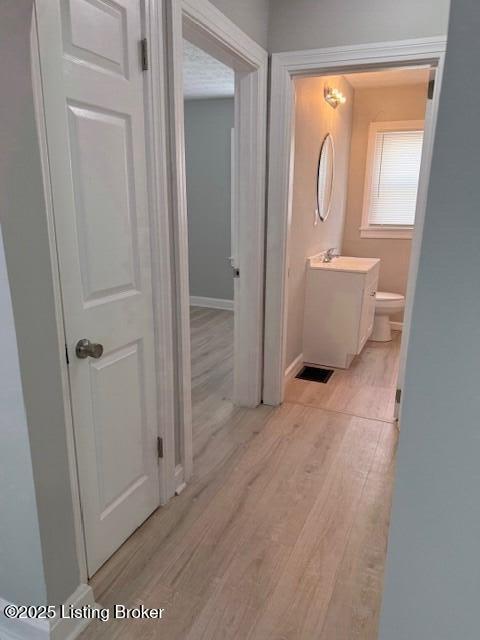 610 Compton St, Louisville, KY 40208 - corridor with light wood finished floors, visible vents, a sink, and baseboards