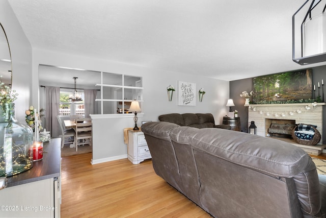 living area featuring a chandelier, a brick fireplace, and light wood finished floors