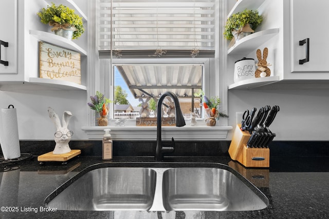 details with open shelves, white cabinets, a sink, and dark stone countertops