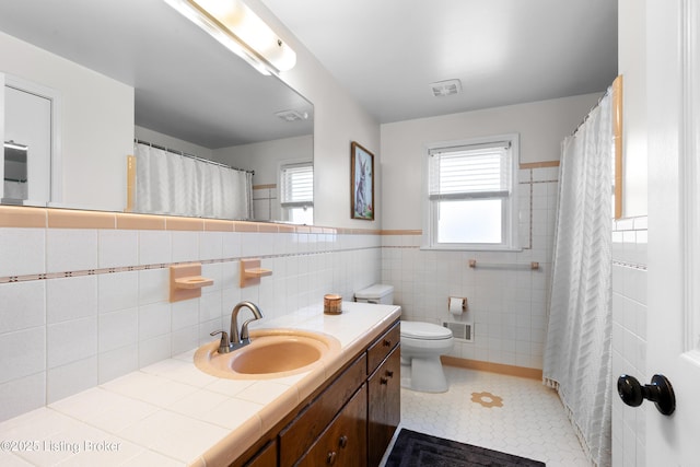 full bathroom with toilet, vanity, visible vents, and tile walls