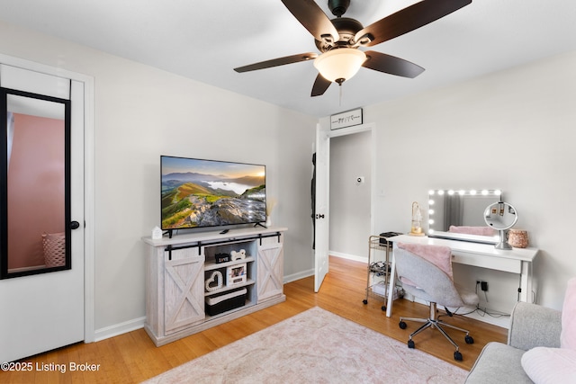 home office featuring light wood-type flooring, a ceiling fan, and baseboards