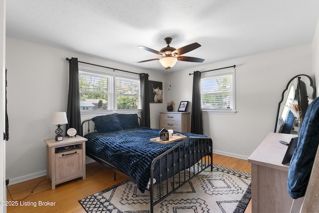 bedroom with light wood finished floors, a ceiling fan, and baseboards