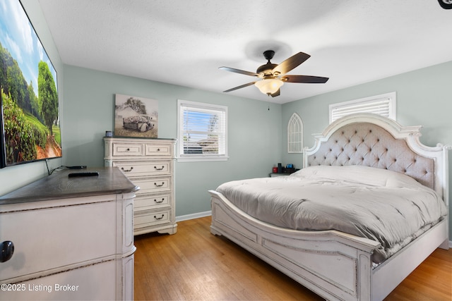 bedroom with light wood finished floors, baseboards, and a ceiling fan