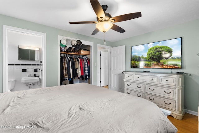 bedroom featuring a ceiling fan, a sink, a closet, connected bathroom, and light wood-type flooring