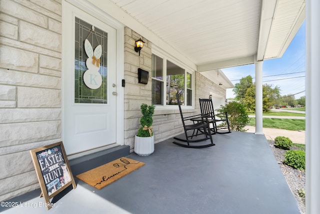 view of exterior entry with stone siding and covered porch