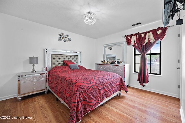 bedroom featuring an inviting chandelier, wood finished floors, and baseboards