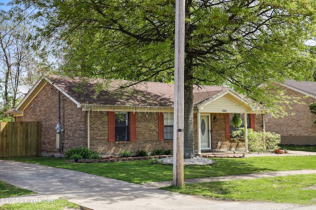 ranch-style home featuring fence, brick siding, a front yard, and roof with shingles