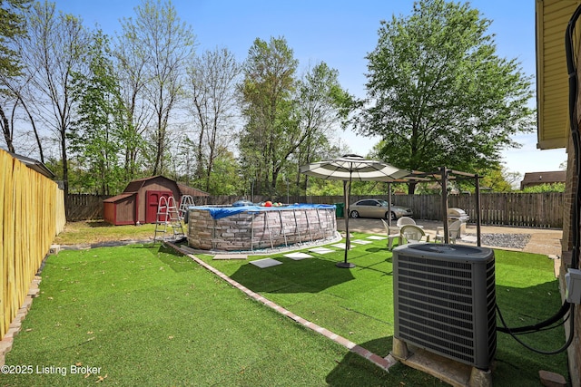 view of yard with central AC, a fenced backyard, an outbuilding, a fenced in pool, and a storage unit