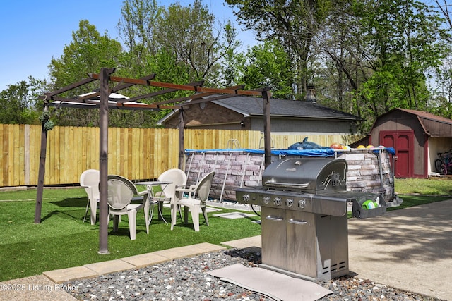 view of patio / terrace with fence, grilling area, a storage unit, and an outdoor structure