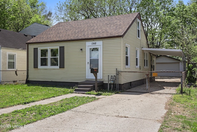 bungalow-style house with roof with shingles, a carport, concrete driveway, fence, and an outdoor structure