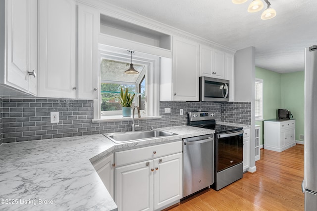 2807 Alice Ave, Louisville, KY 40220 - kitchen featuring appliances with stainless steel finishes, a sink, white cabinetry, backsplash, and light wood finished floors
