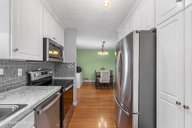 2807 Alice Ave, Louisville, KY 40220 - kitchen with stainless steel appliances, white cabinets, decorative backsplash, light wood finished floors, and a textured ceiling