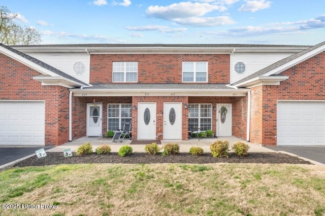 traditional home with a front lawn, a porch, brick siding, an attached garage, and aphalt driveway