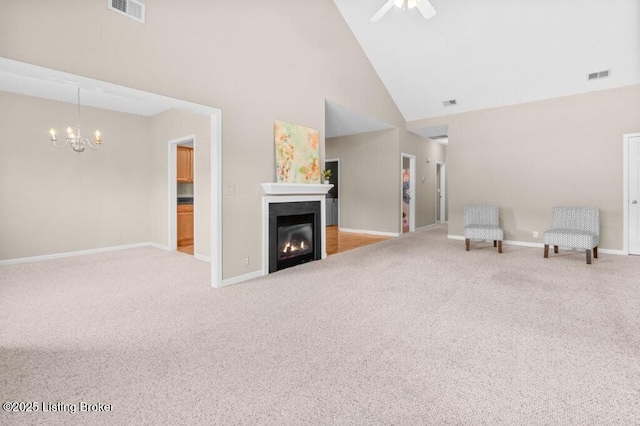unfurnished room featuring carpet, a glass covered fireplace, visible vents, and high vaulted ceiling