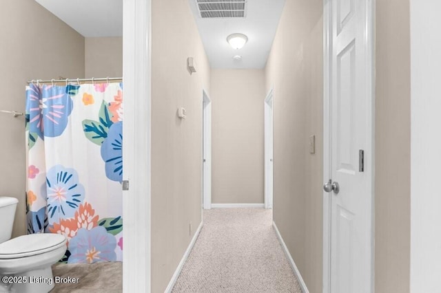 hall featuring carpet floors, visible vents, and baseboards