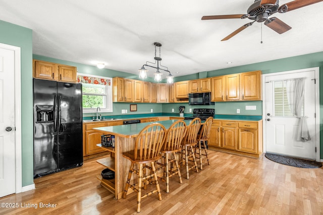 5502 Highpoint Dr, Crestwood, KY 40014 - kitchen featuring black appliances, light wood-style flooring, a kitchen island, a breakfast bar area, and pendant lighting