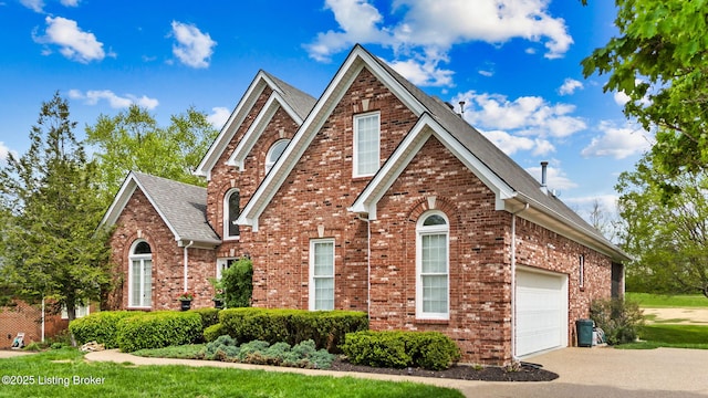 traditional home with an attached garage, a shingled roof, driveway, and brick siding