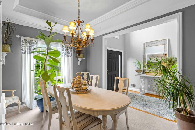 dining area featuring a tray ceiling, baseboards, an inviting chandelier, and crown molding