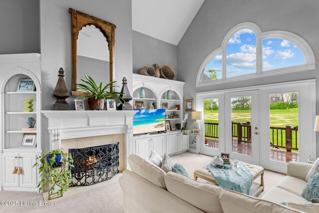 carpeted living room with a fireplace with flush hearth and high vaulted ceiling