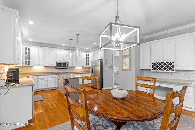 dining room featuring recessed lighting, light wood-style flooring, crown molding, and an inviting chandelier