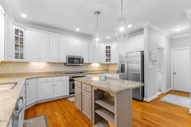 kitchen featuring white cabinets, stainless steel appliances, decorative backsplash, and ornamental molding