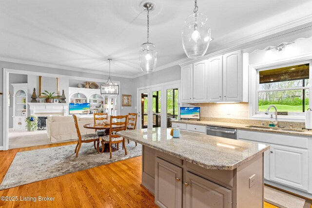 kitchen featuring light wood finished floors, a center island, a sink, and white cabinetry