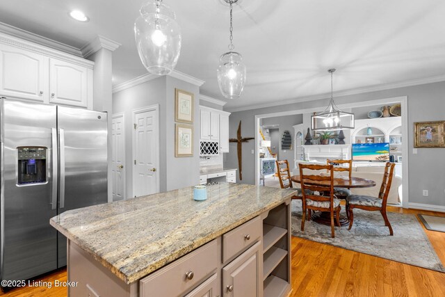 kitchen with white cabinets, crown molding, light wood-type flooring, and stainless steel fridge