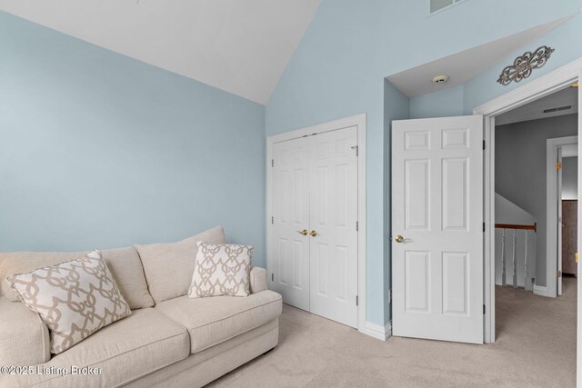 living area featuring lofted ceiling, baseboards, visible vents, and light colored carpet
