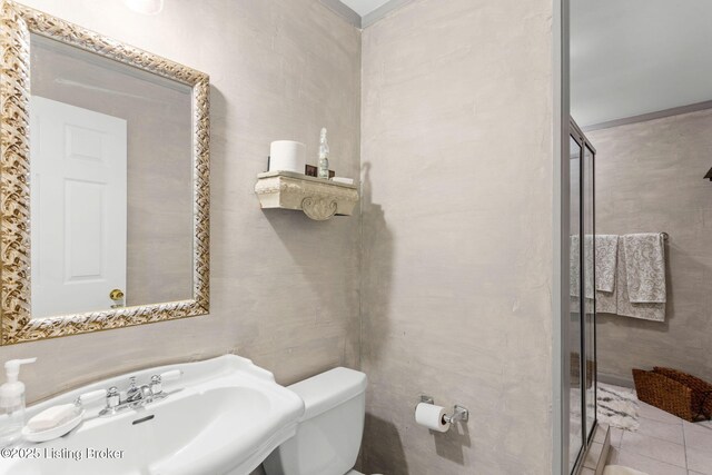 bathroom featuring toilet, a sink, and a stall shower