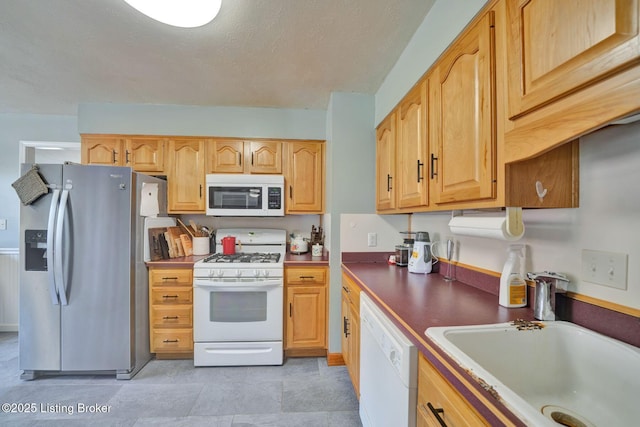 kitchen with a textured ceiling, a sink, and white appliances