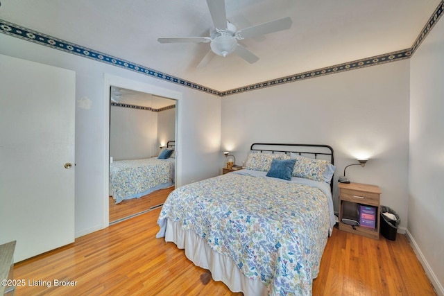bedroom featuring baseboards, wood finished floors, a ceiling fan, and a closet